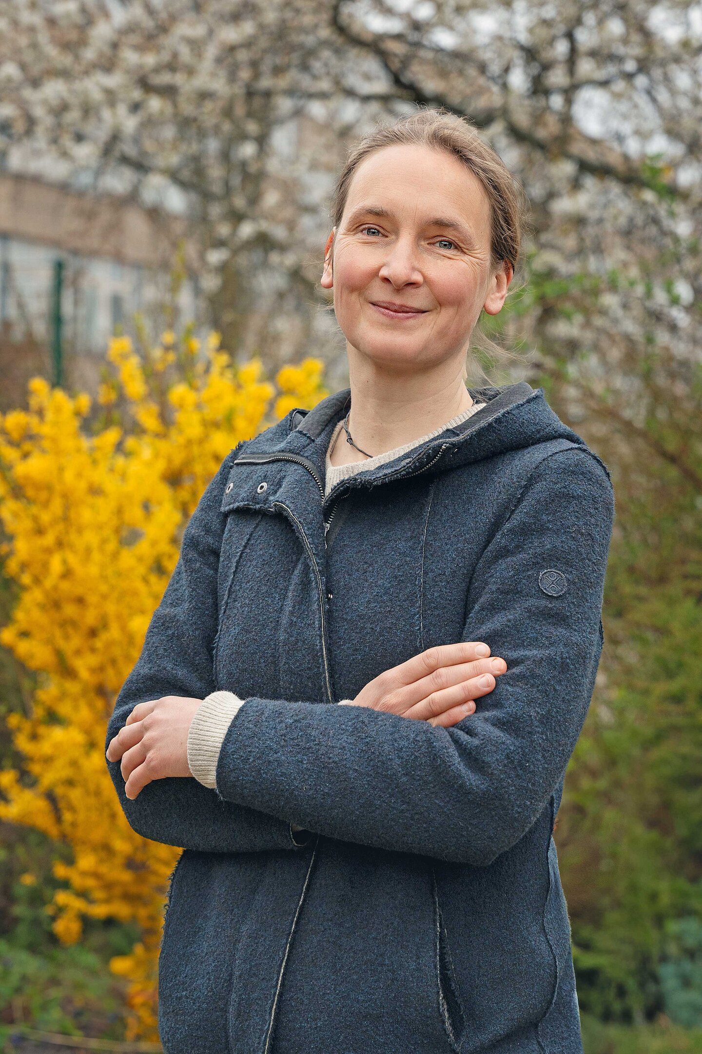 Prof. Dr. Ulrike Igel eine Frau steht vor einem gelb blühenden Baum