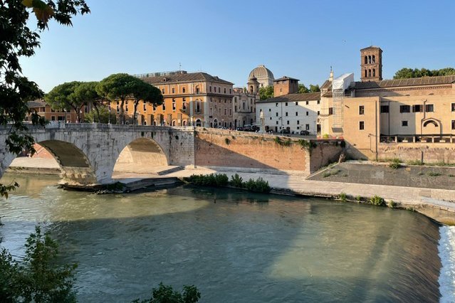 Pastellfarbende Gebäude an einem Fluss mit steinerner Brücke.