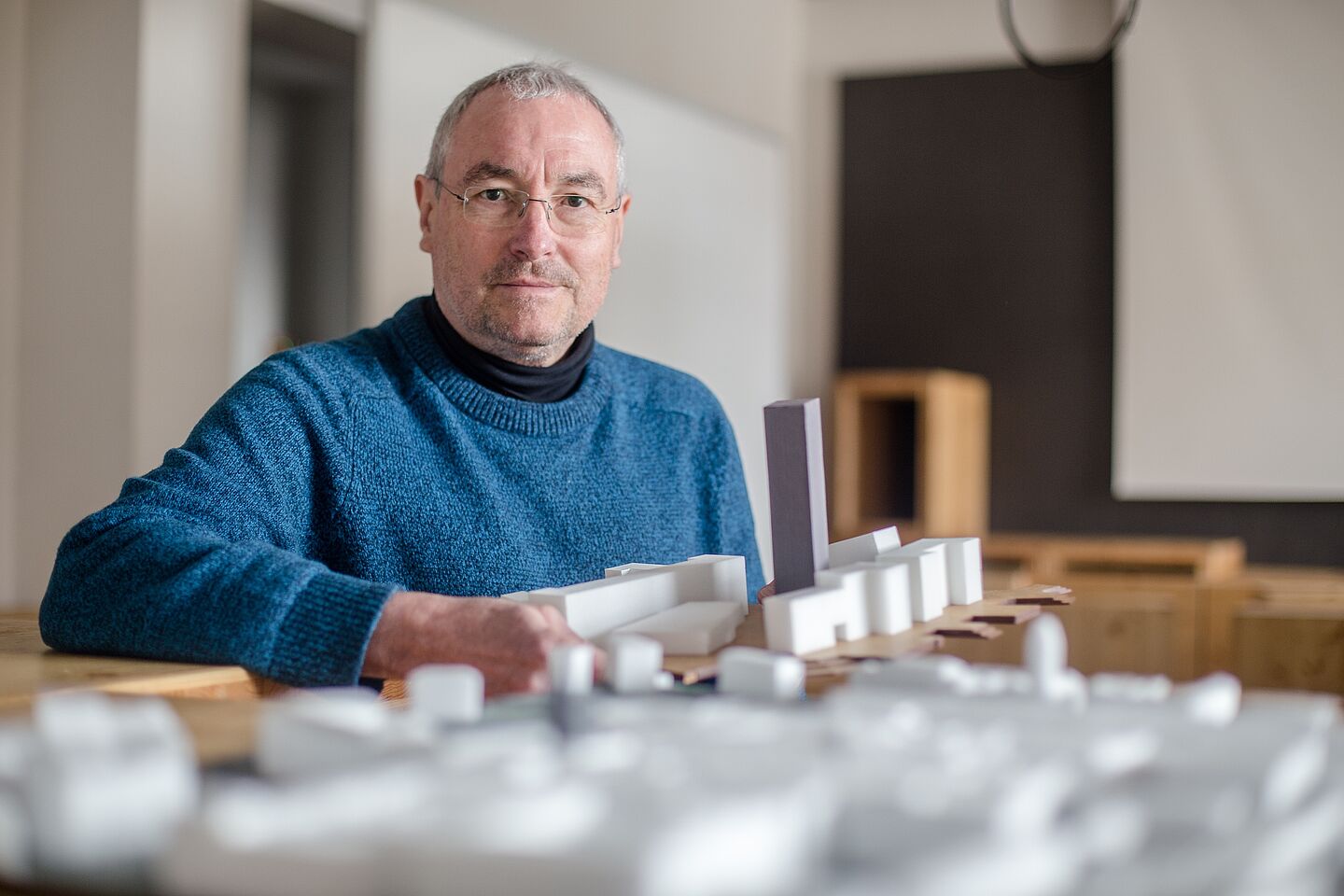 Prof. Ronald Scherzer-Heidenberger. (Foto: Robert Weinhold/HTWK Leipzig) Mann mit Architekturmodellen.