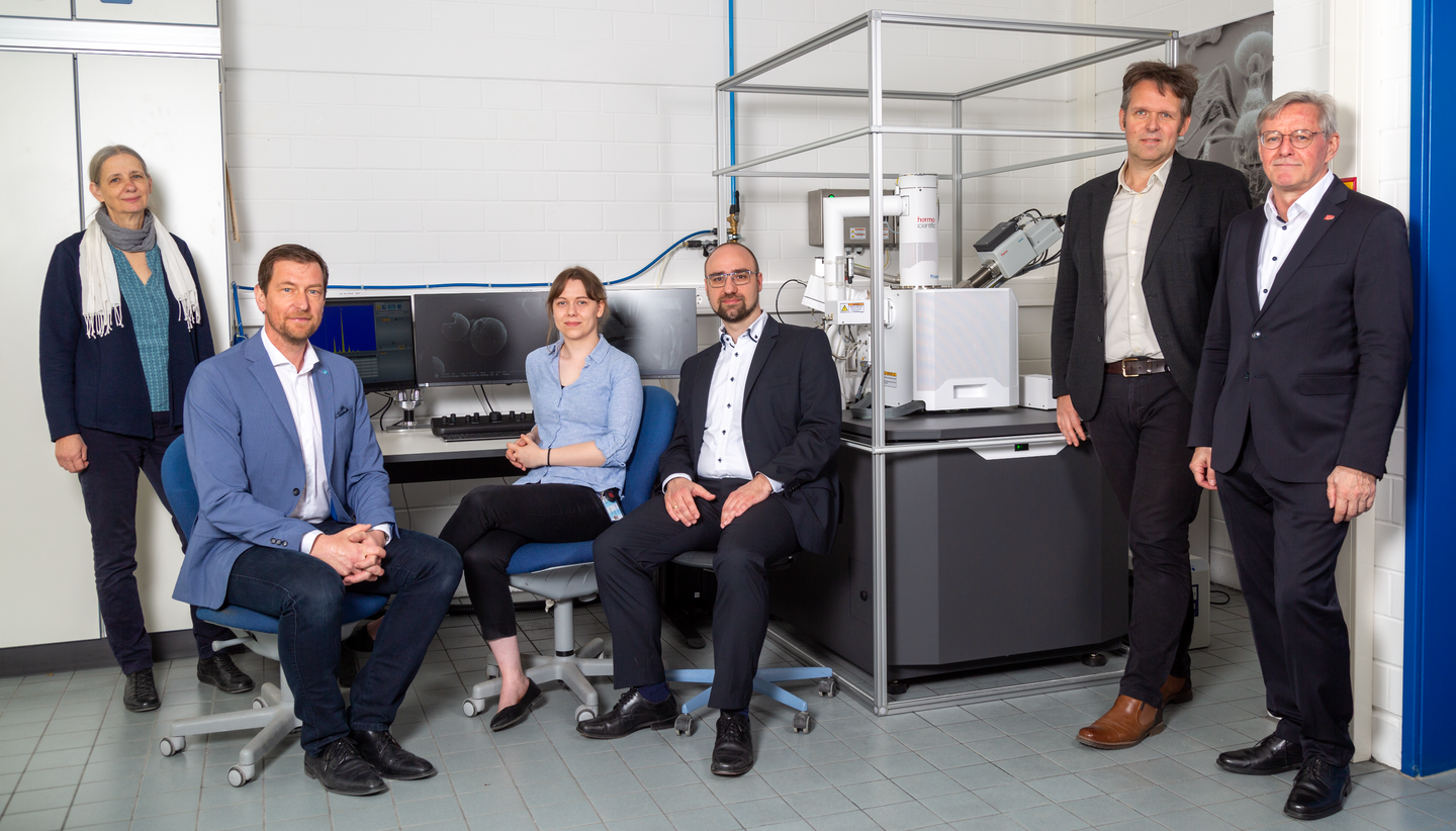 Sechs Personen in einem Labor an einem Gerät