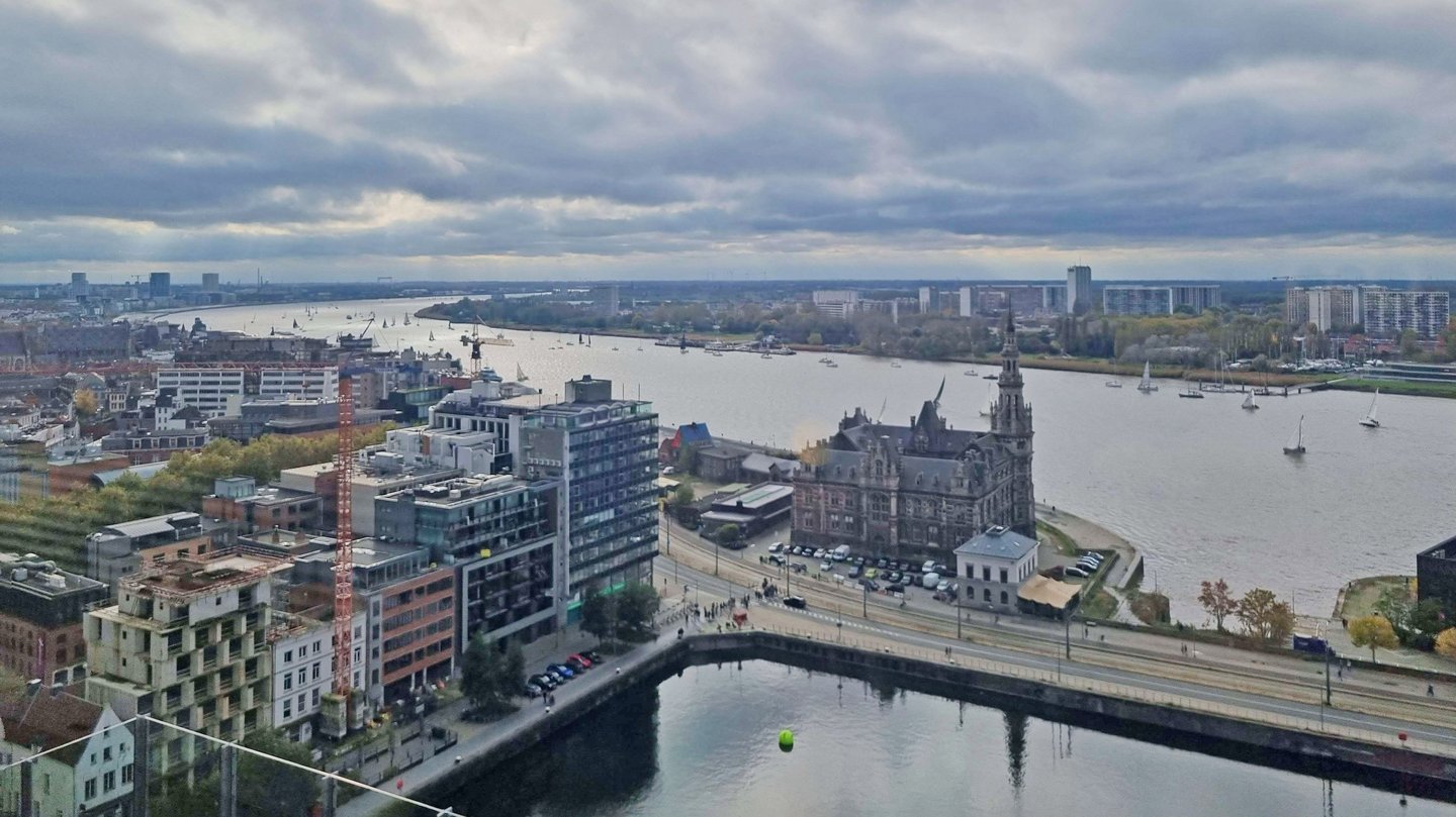 Blick aus der Vogelperspektive auf Antwerpen mit modernen Gebäuden und einem breiten Fluss.