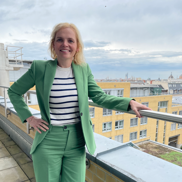 Frau in grünem Hosenanzug steht auf einer Terrasse