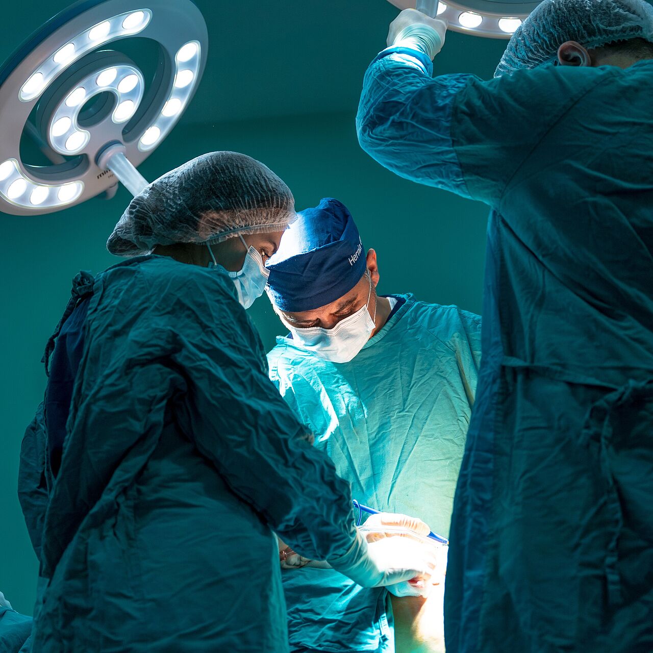 Drei Mediziner operieren einen Patienten. LED-Lampen sorgen dabei für eine gute Beleuchtung.