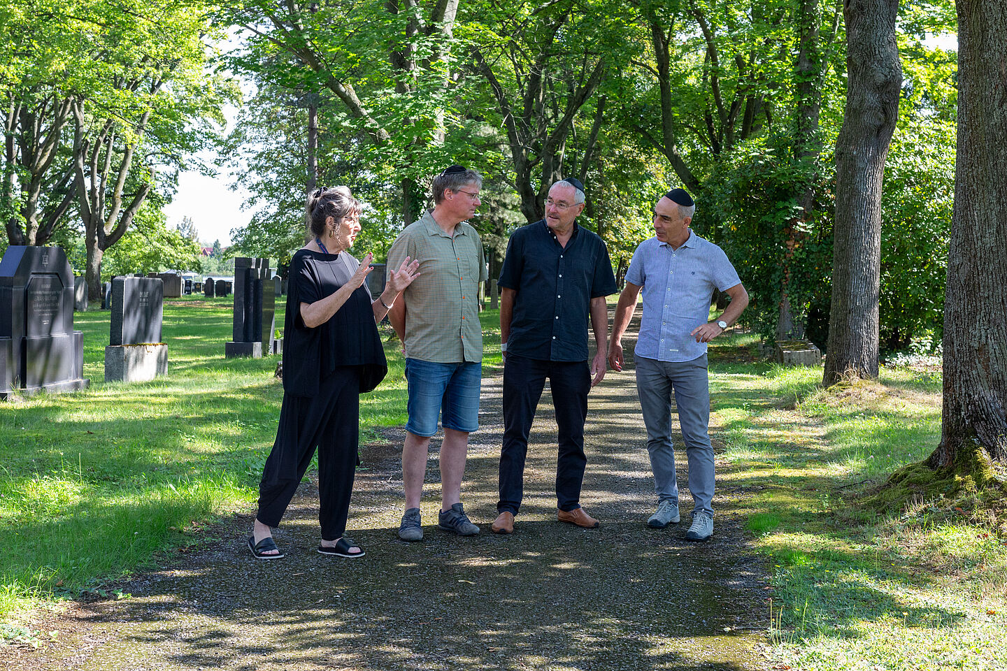 Besprechung auf dem Friedhof unter grünen Baumkronen