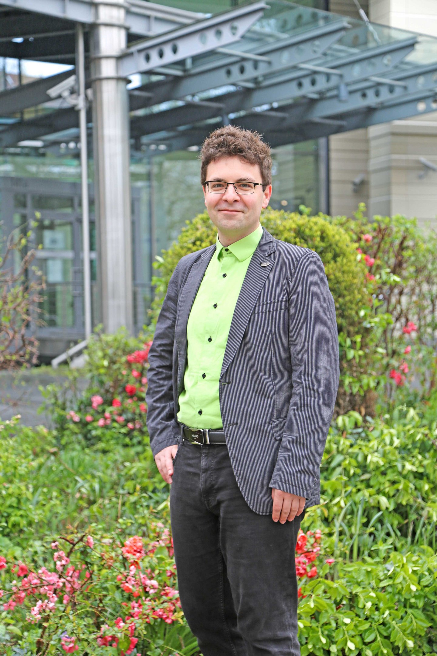 Dr. Markus Gentzsch ein Mann steht vor einem gläsernem Gebäude mit Säule und mit Begrünung