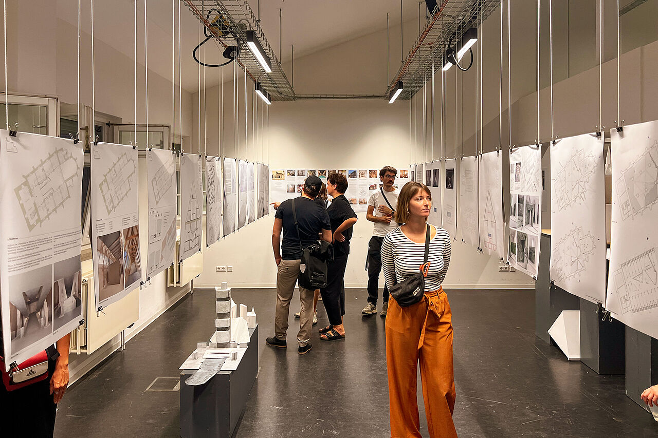 Gäste der Ausstellung laufen entlang von der Decke hängenden Poster