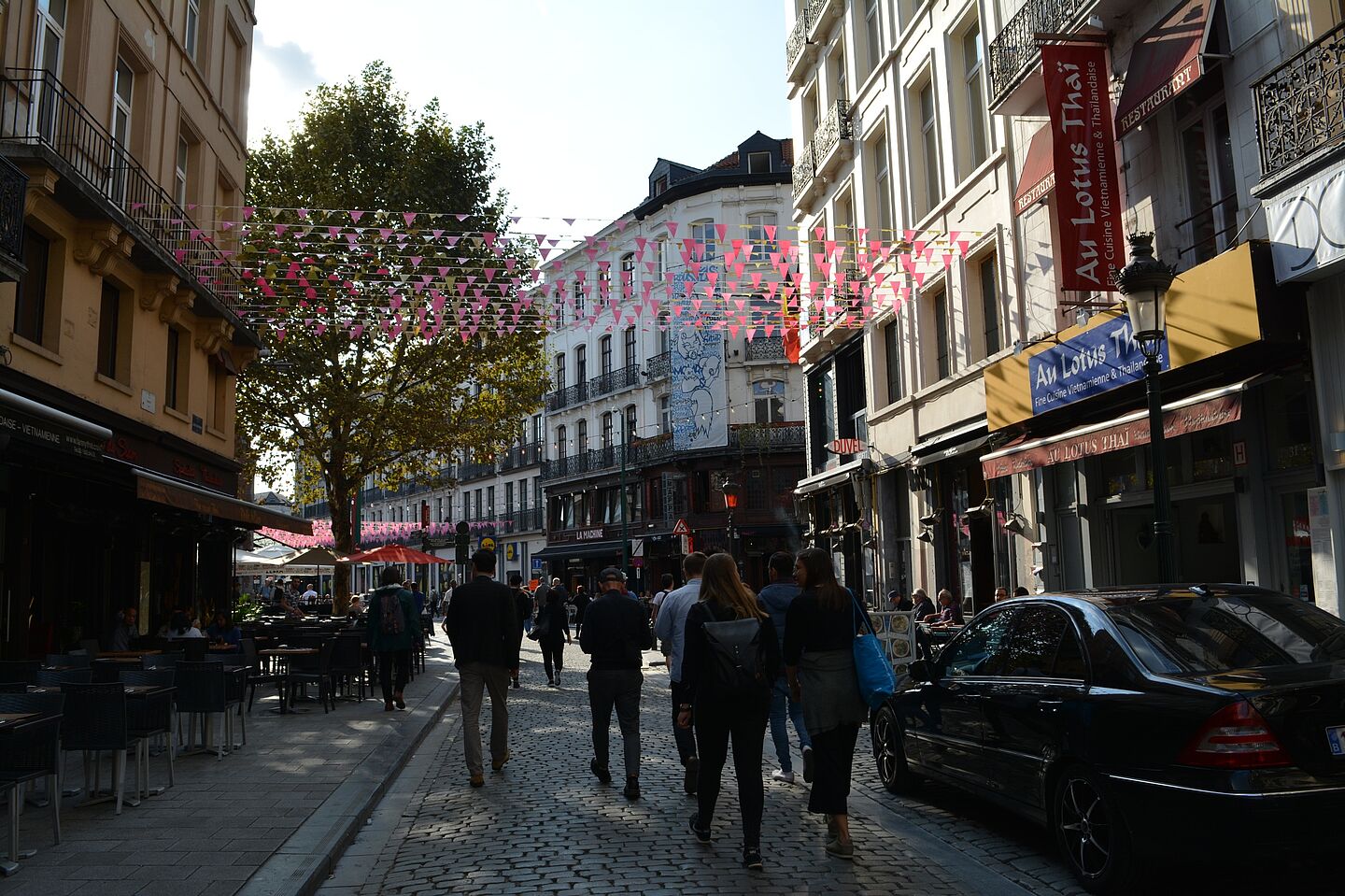 Blick in eine schmale Gasse. Vor den mehrgeschossigen Häusern sind Freisitze aufgebaut, die Straße ist mit Kopfsteinpflaster gepflastert.