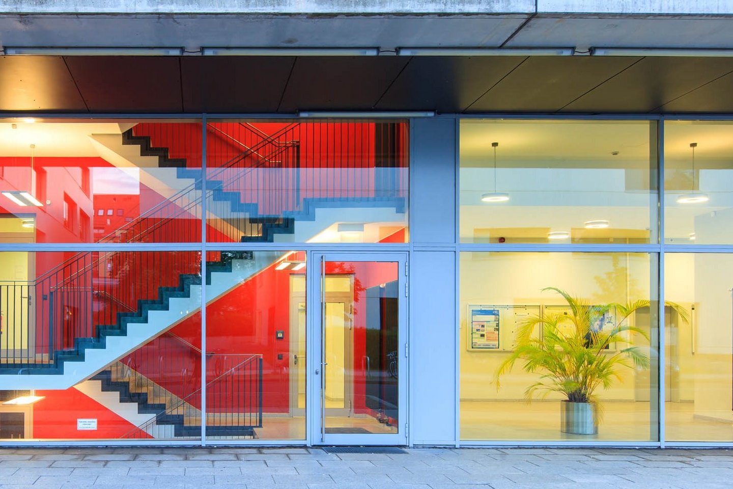 Glasfront eines Hochschulgebäudes mit Blick ins Treppenhaus und in einen Flur.