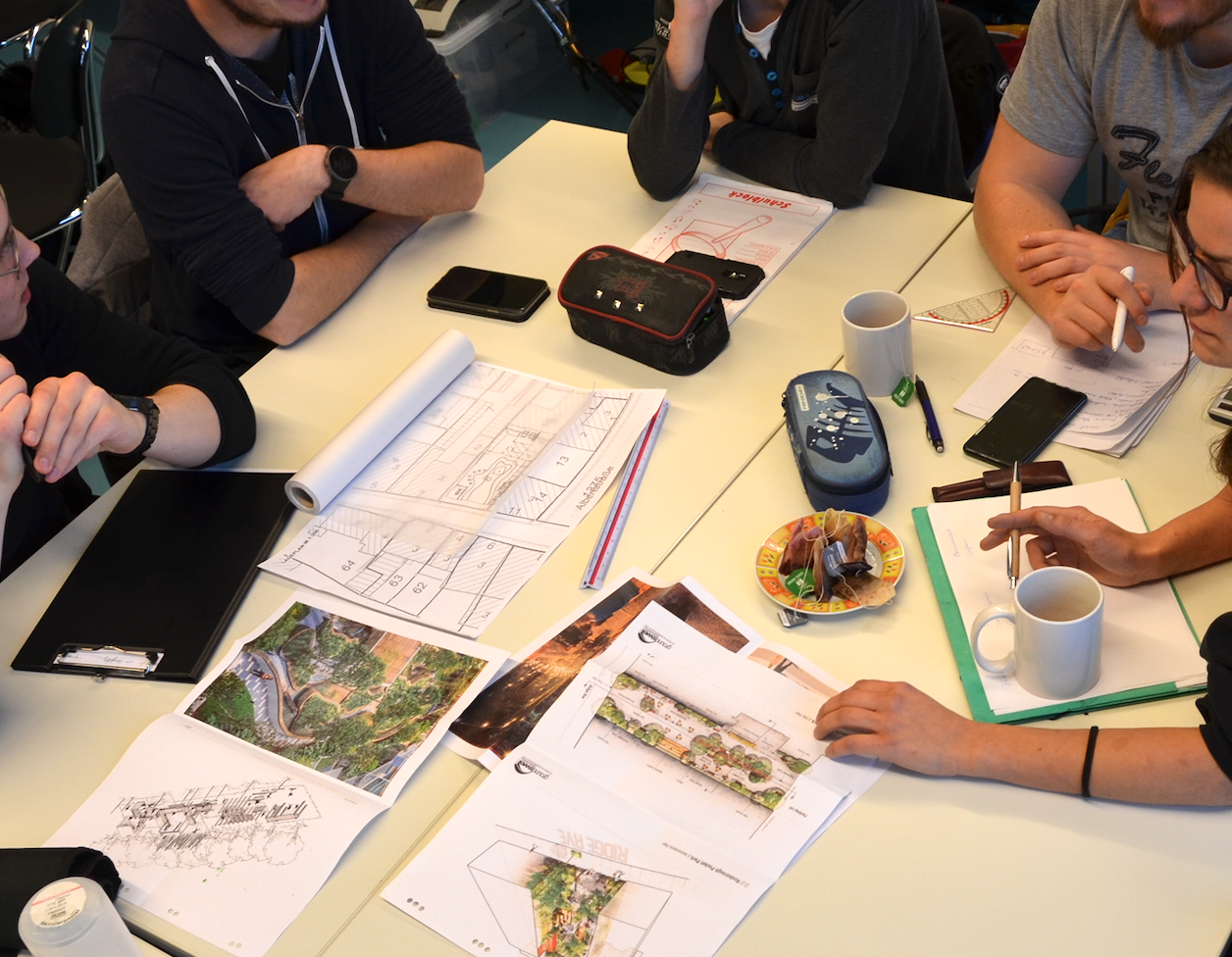 Gemeinsames Entwerfen: Studierende der HTWK Leipzig und der Hochschule Zittau/Görlitz. (Foto: RSH) Draufblick auf Arbeitstisch mit vielen Händen und Papieren.